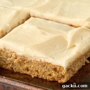 square piece of cake with cream cheese frosting in jelly roll pan.