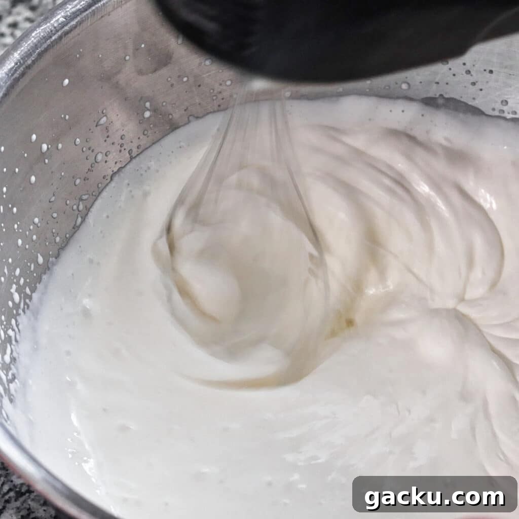 Gluten-Free Lemon Pie Recipe: Zesty Tart with Buttery Crust 11 whipping heavy cream in a large stainless steel bowl using black hand mixer.