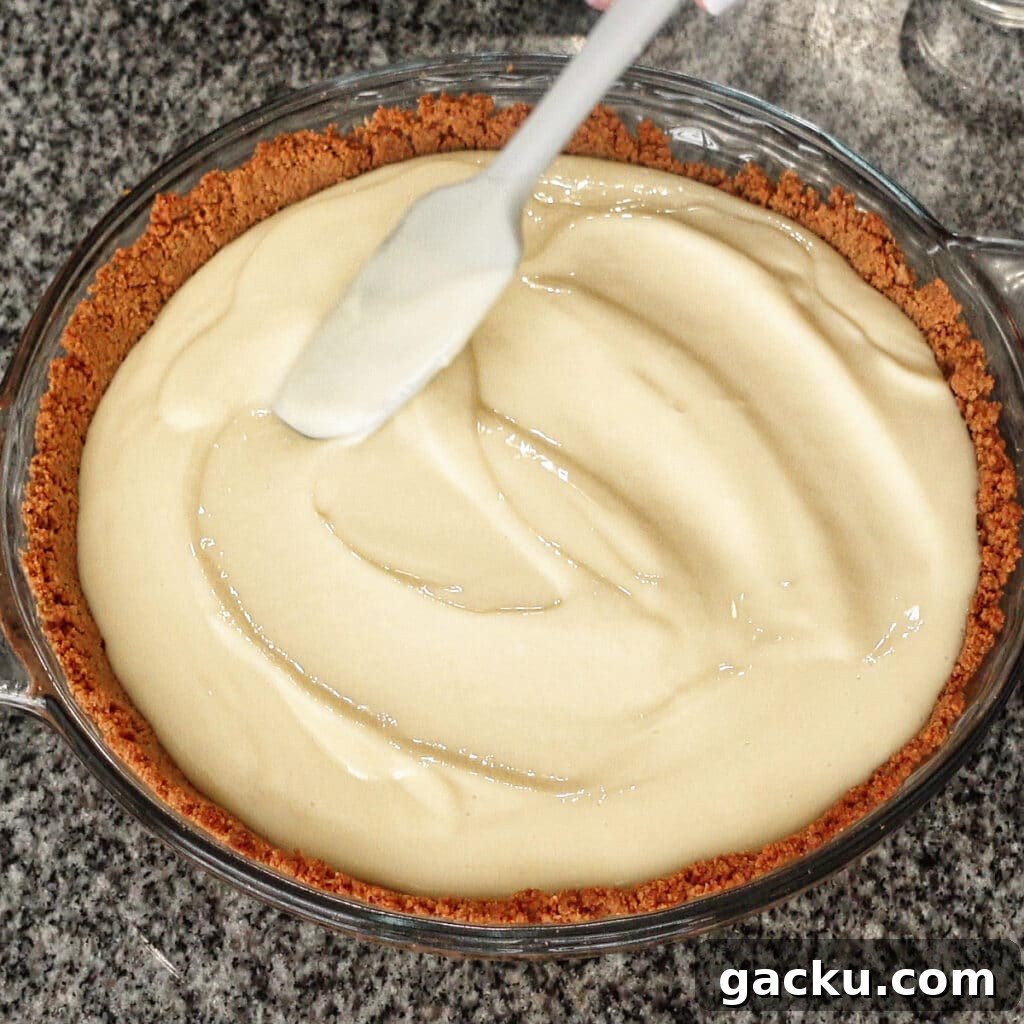 Gluten-Free Lemon Pie Recipe: Zesty Tart with Buttery Crust 10 smoothing top of lemon cream pie with silicone spatula.