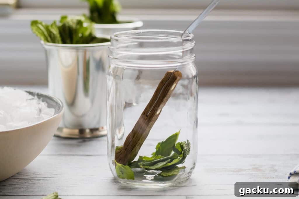 Classic Mint Julep Recipe: How to Make the Southern Cocktail 4 mint leaves being muddled in mason jar