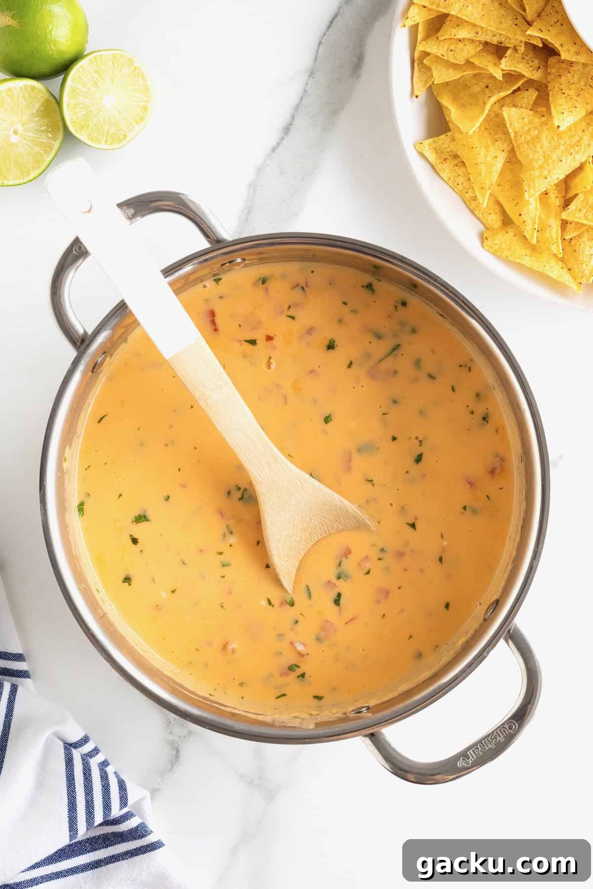 Stovetop Queso Recipe: Creamy, Quick Melted Cheese Dip 11 A wooden spoon resting in a large stainless steel pot of queso.