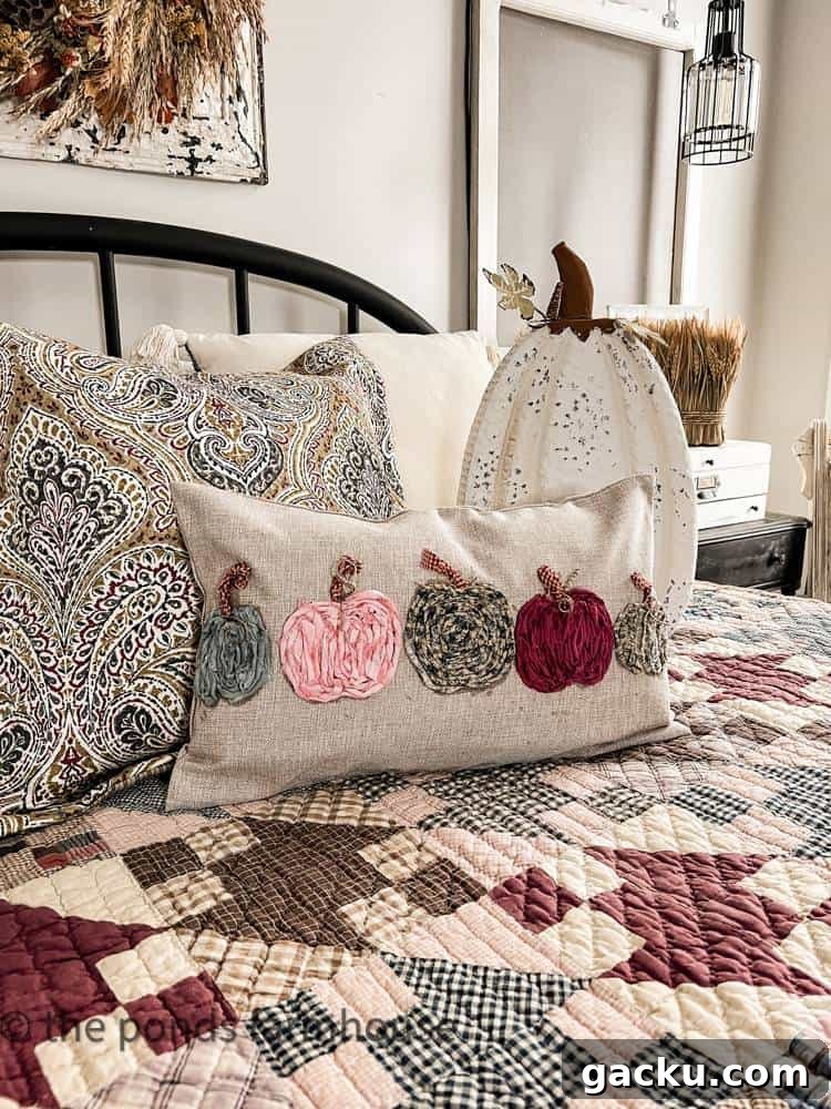 15 Fall DIY Home Decor Crafts to Transform Your Space 3 knit pumpkins across front of neutral pillow on bed with quilt