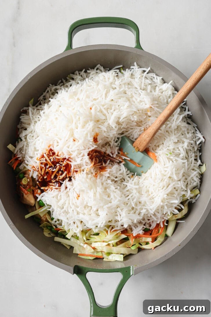 Indo-Chinese Basmati Fried Rice Recipe 11 Cooked rice and sauce added to pan with sautéed chicken and vegetables ready to be mixed together.