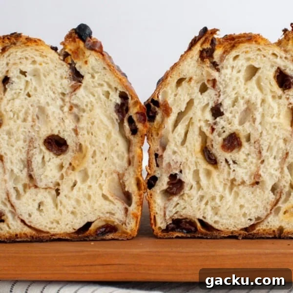Sourdough cinnamon raisin bagel bread cut in half sitting on a cutting board.