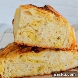 Sourdough almond croissant loaf on a cutting board with layers of frangipane almond filling throughout.