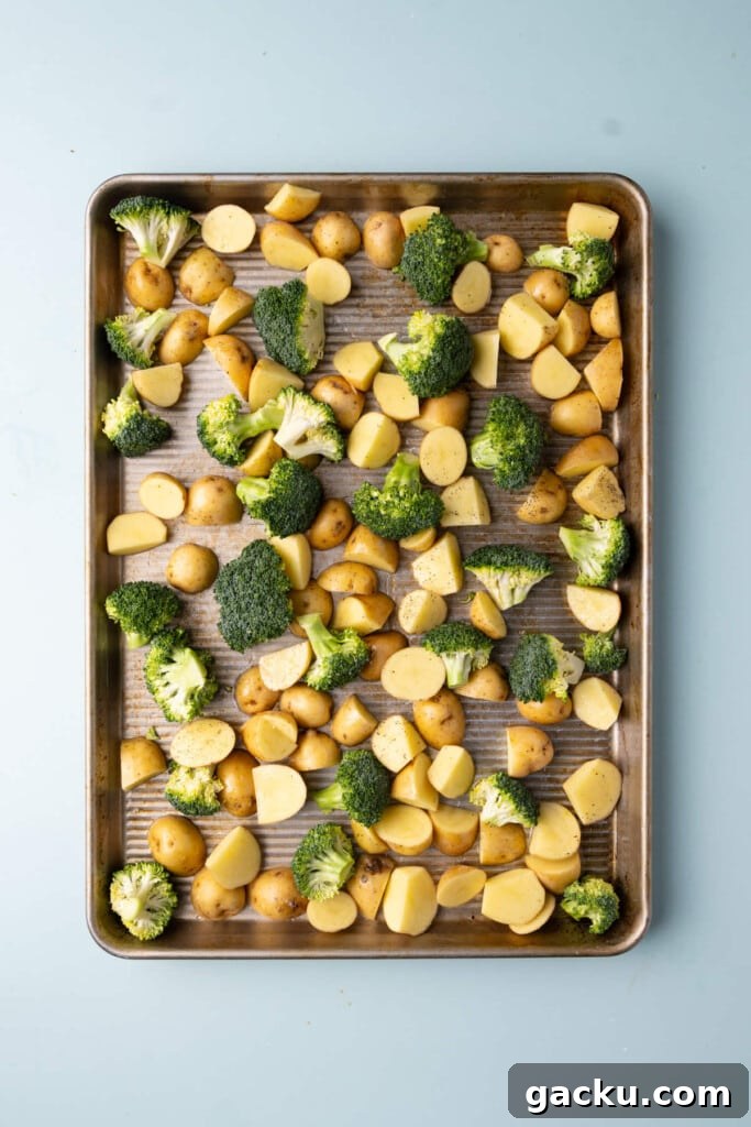 30-Minute Roasted Baby Potatoes & Broccoli with Garlic Butter 6 Prepped broccoli and potatoes coated in olive oil, salt, and pepper on a sheet pan.