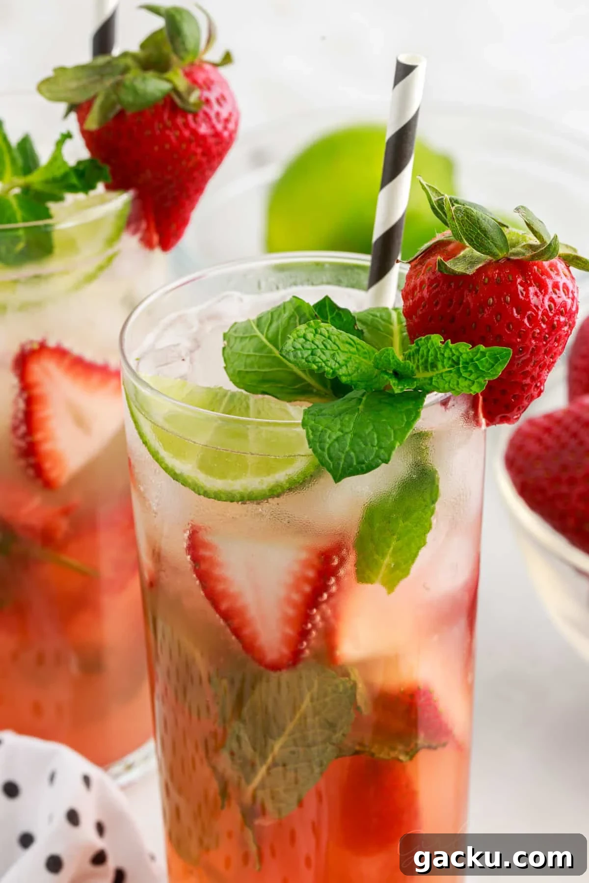 Two Strawberry Mojito in tall glasses garnished with mint and strawberries.