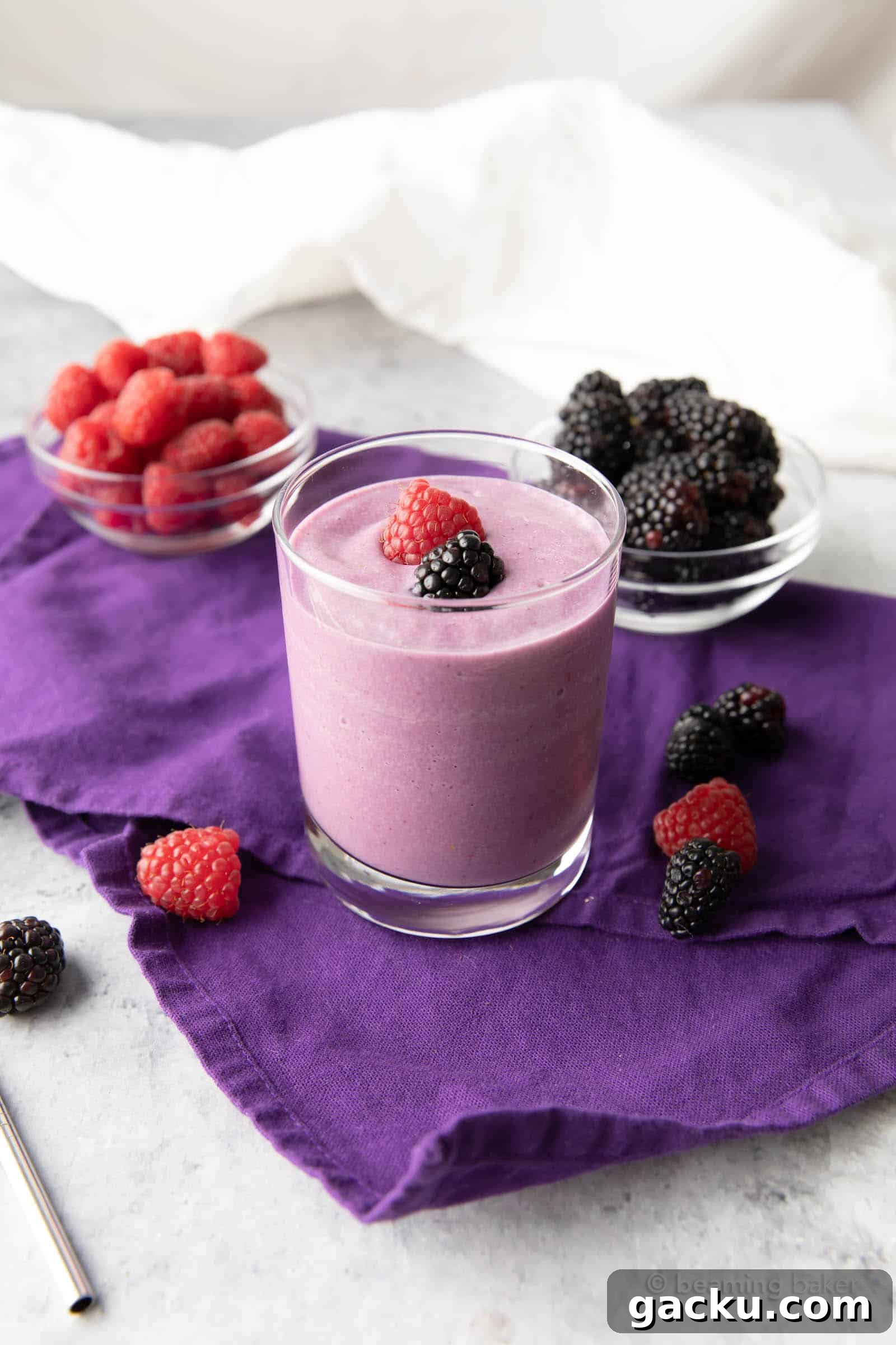 Low carb berry smoothie on a purple tablecloth with raspberries and blackberries surrounding it