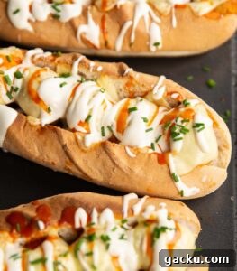 Buffalo Chicken Meatball Subs close up shot of 3 buffalo chicken meatball subs on black baking tray