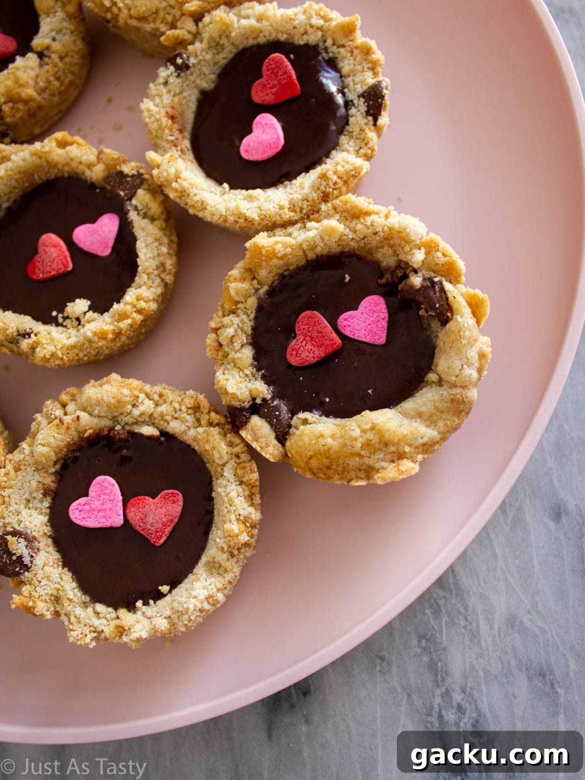 Chocolate Chip Cookie Cups Recipe — Mini Baked Cookie Desserts 2 Chocolate chip cookie cups filled with chocolate ganache and topped with heart sprinkles.