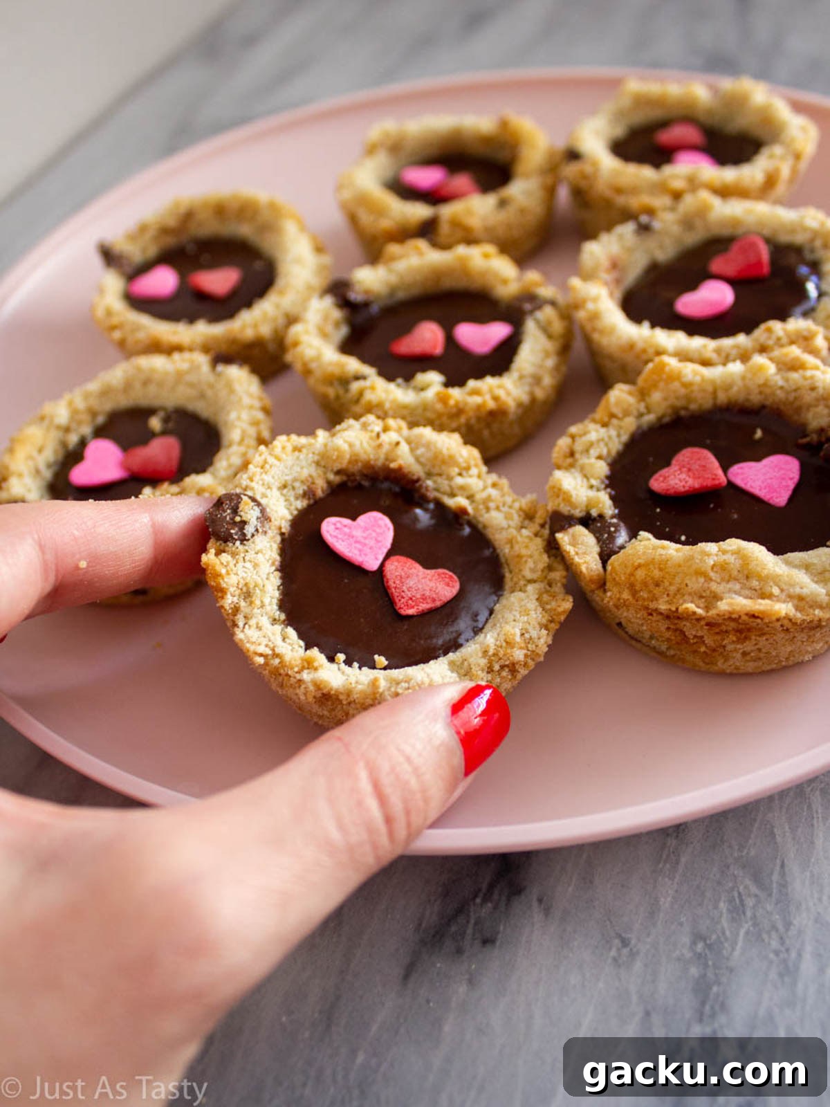 Chocolate Chip Cookie Cups Recipe — Mini Baked Cookie Desserts 3 Chocolate chip cookies filled with ganache on a pink plate.