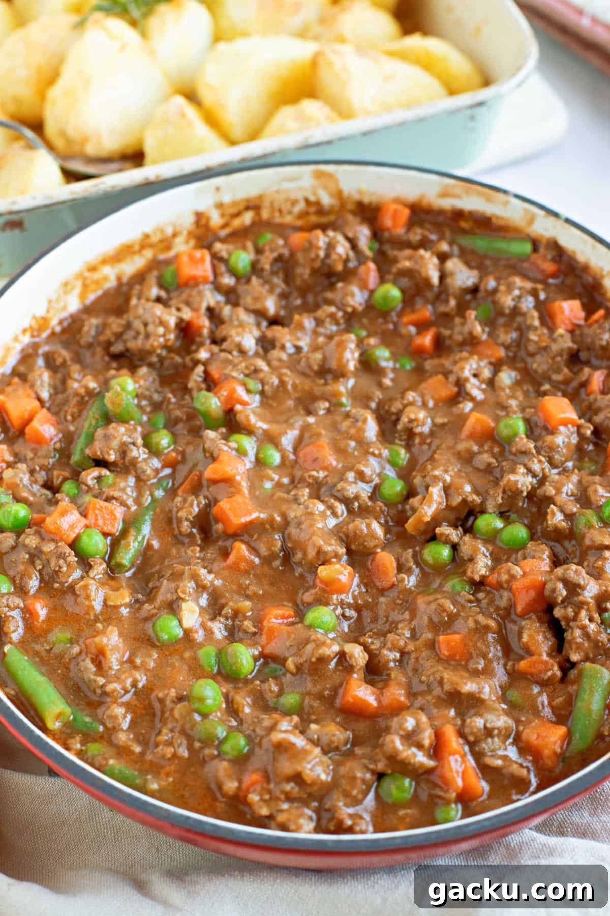 Savory Mince Recipe: Quick Homemade Beef Mince for Dinner 2 A pan of savoury mince with roast potatoes in the background.