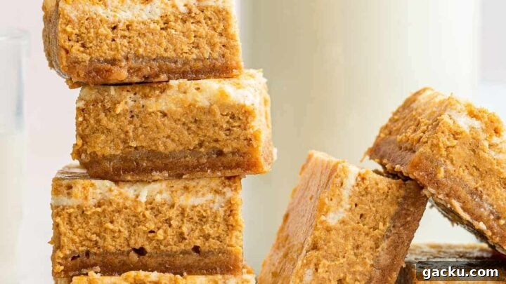 Stacks of pumpkin cheesecake bars with swirled top and glass of milk.
