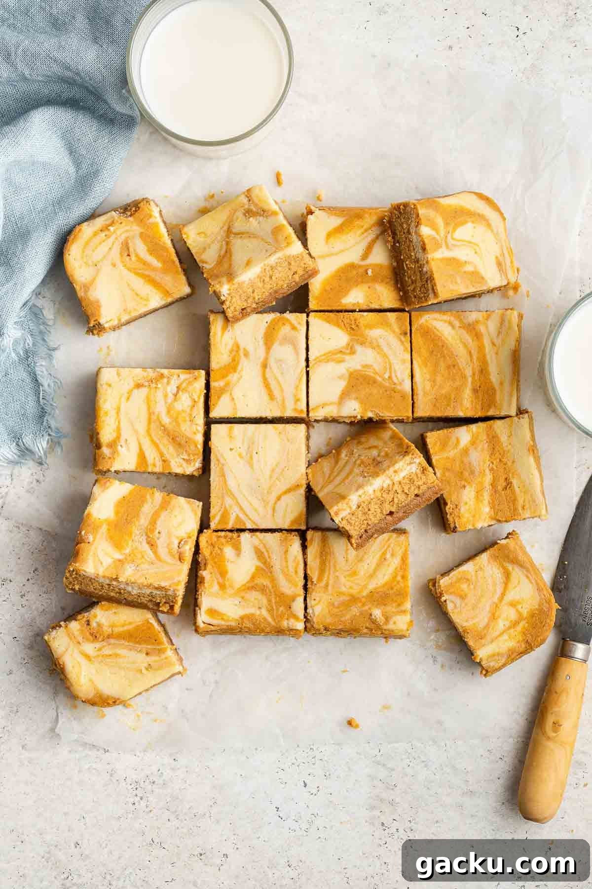 Pumpkin Cheesecake Bars Recipe — Creamy Spiced Autumn Dessert 3 Overhead shot of 16 orange and white swirled dessert custard slices.