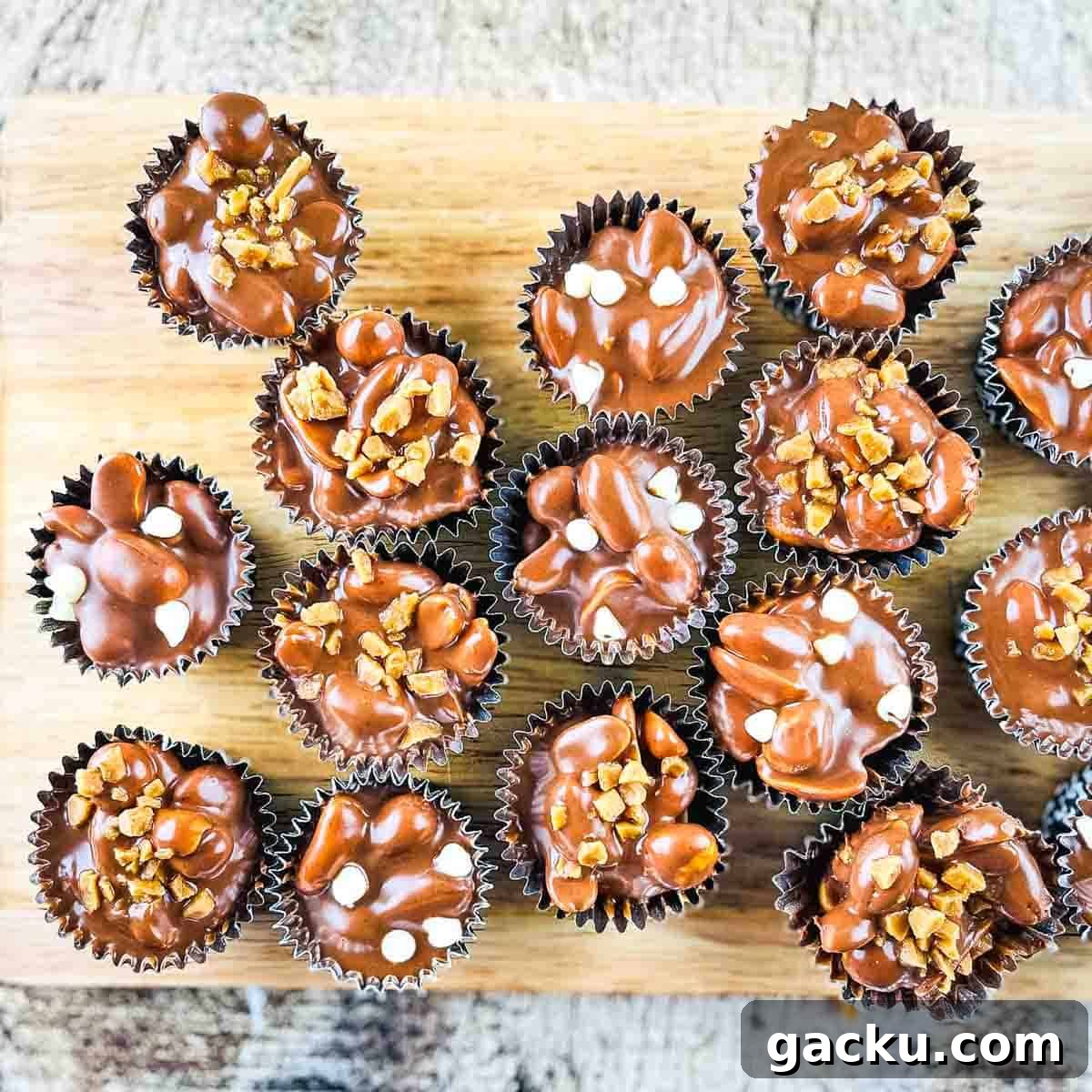 Crockpot candy clusters in muffin liners on a wooden tray.
