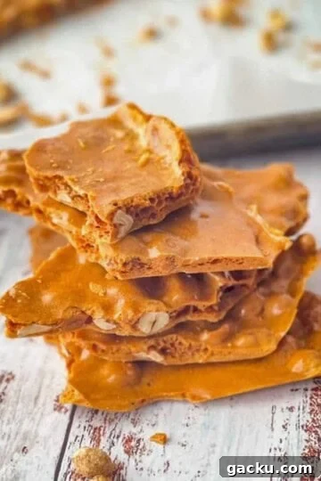 Soft peanut brittle stacked on top of each other with a pan of the rest of the brittle in the background.