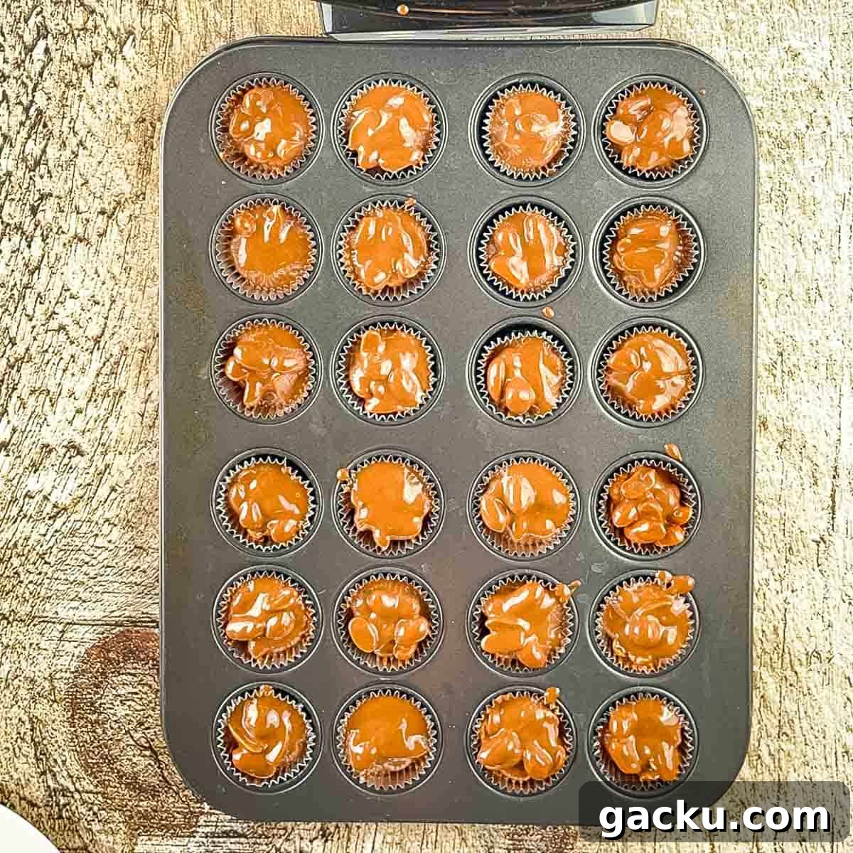 The melted chocolate mixture in muffin liners in a muffin tin.