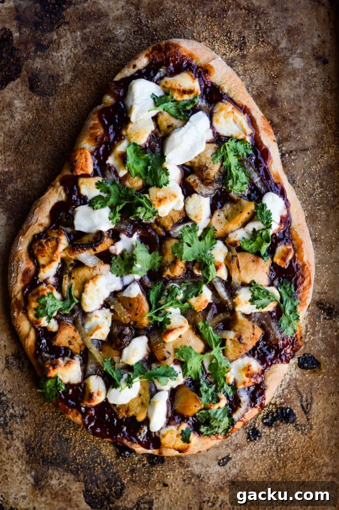 A cooked pizza with raspberry jalapeno sauce, chicken, caramelized onions, goat cheese and cilantro.