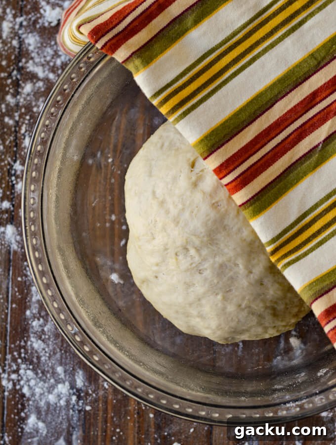 A glass bowl with a ball of pizza dough ready to rise.