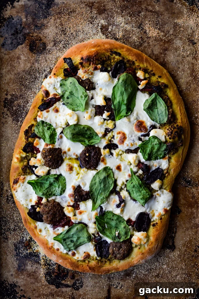 A cooked mediterranean pizza with lamb, feta, mozzarella, kalamata olives and sundried tomatoes.