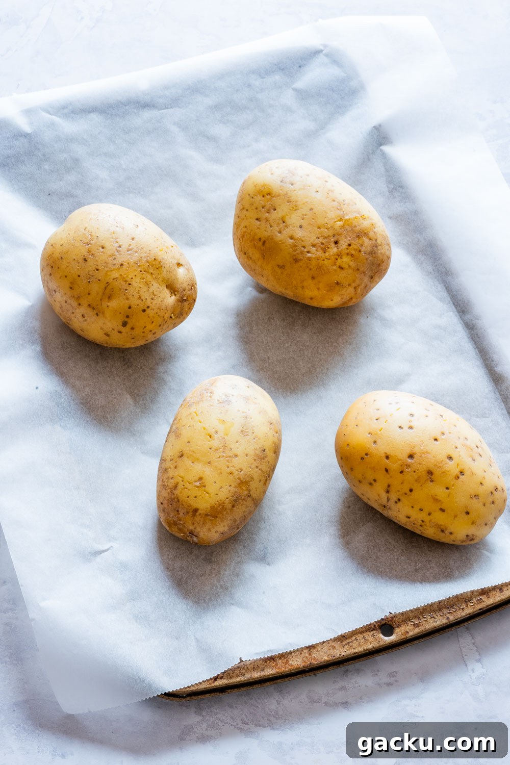 Ultimate Twice-Baked Potatoes Recipe for Crispy, Cheesy Potatoes 4 Four potatoes on the baking tray.