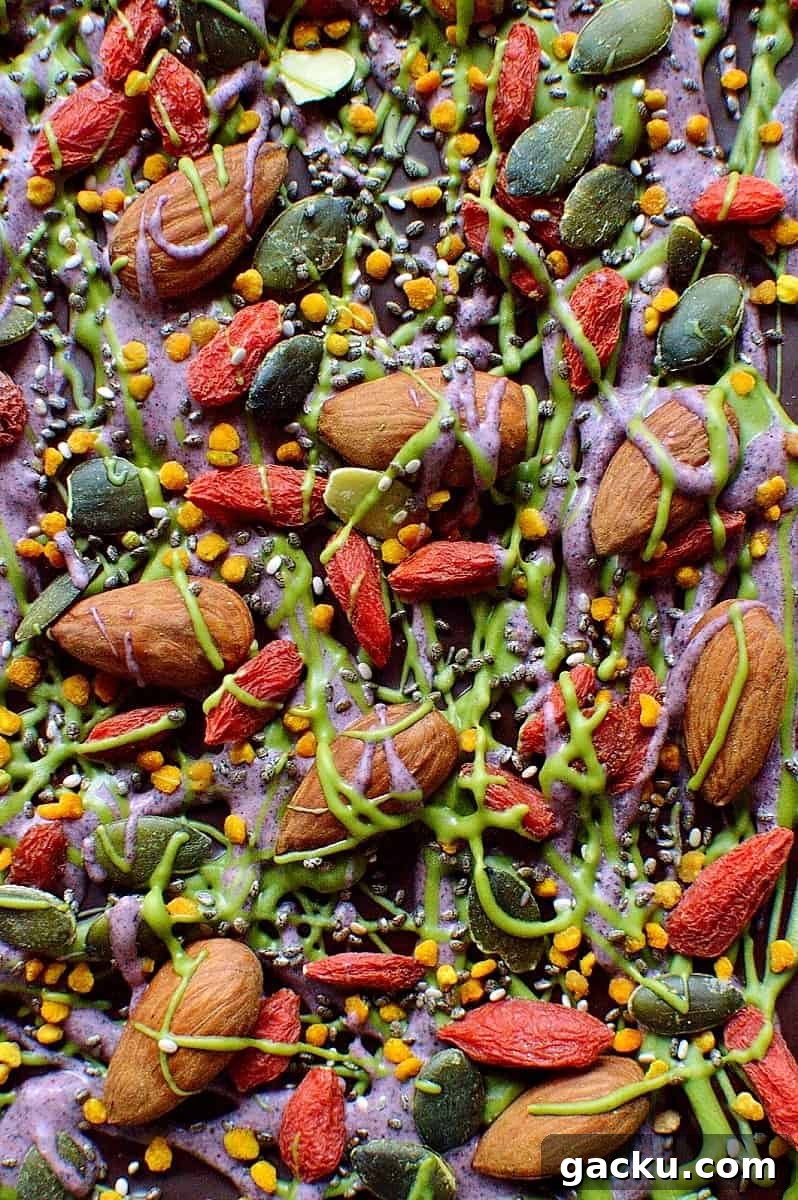 Superfood Chocolate Bark Recipe with Nuts & Seeds 8 Superfood chocolate bark - dark chocolate topped with almonds, goji berries, seeds, bee pollen and white chocolate flavoured with matcha and freeze dried blueberry powder