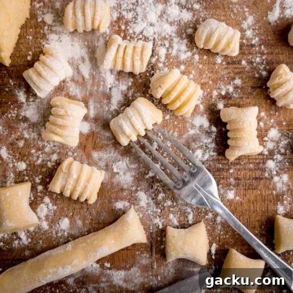 Creamy Baked Gnocchi with Chicken and Parmesan Crisp 8 Gnocchi being cut and shaped on a wooden board. There is a fork in shot - used for rolling