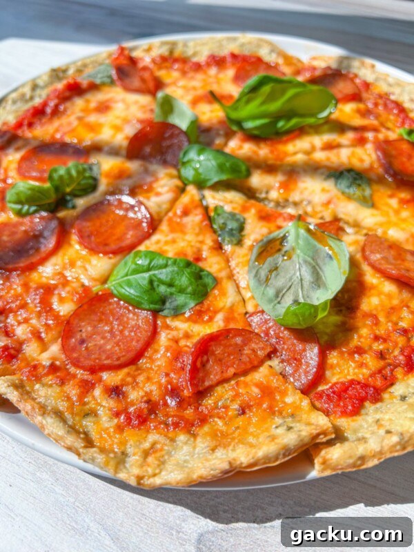 Fluffy Cloud Bread Recipe: Soft, Airy Sandwich Loaf in Minutes 9 A close-up of a Low Carb Pizza topped with pepperoni and fresh basil leaves, sliced into pieces and served on a white plate. The melted cheese and tomato sauce are visible in bright, natural sunlight.