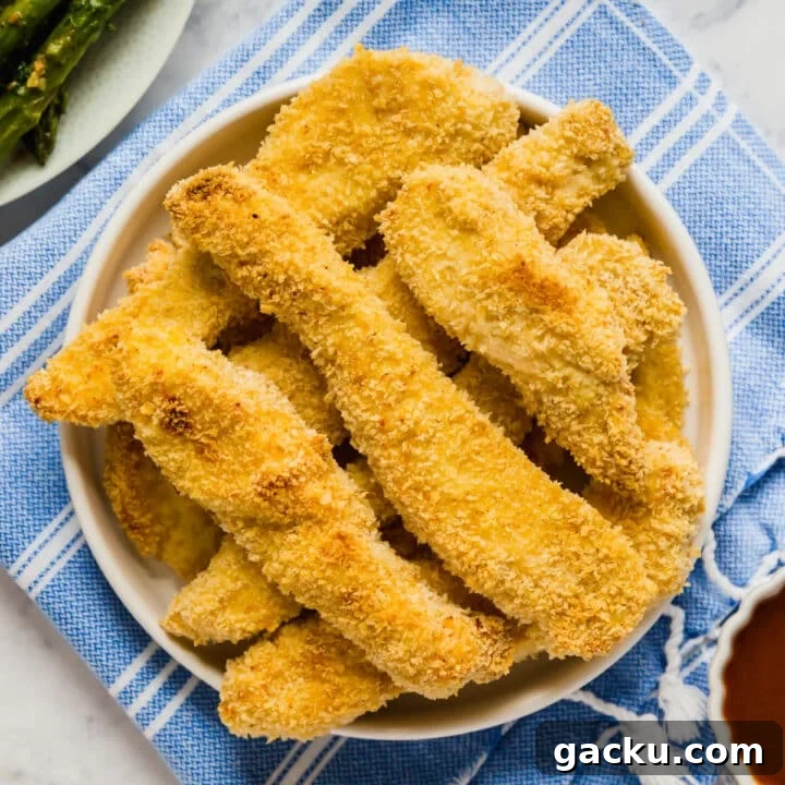 An overhead image of a plate of chicken tenders on a blue and white towel.