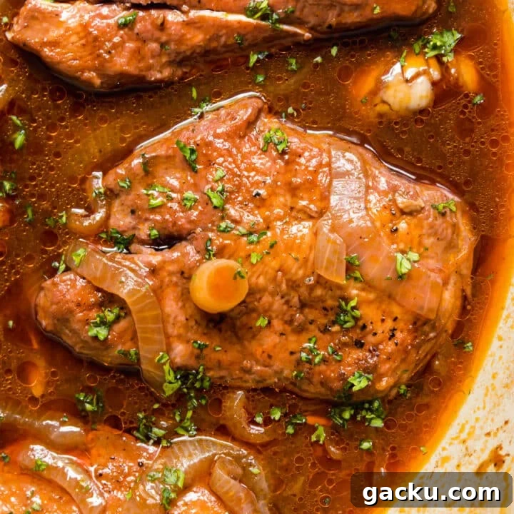A close up image of chicken in wine sauce in the pan.