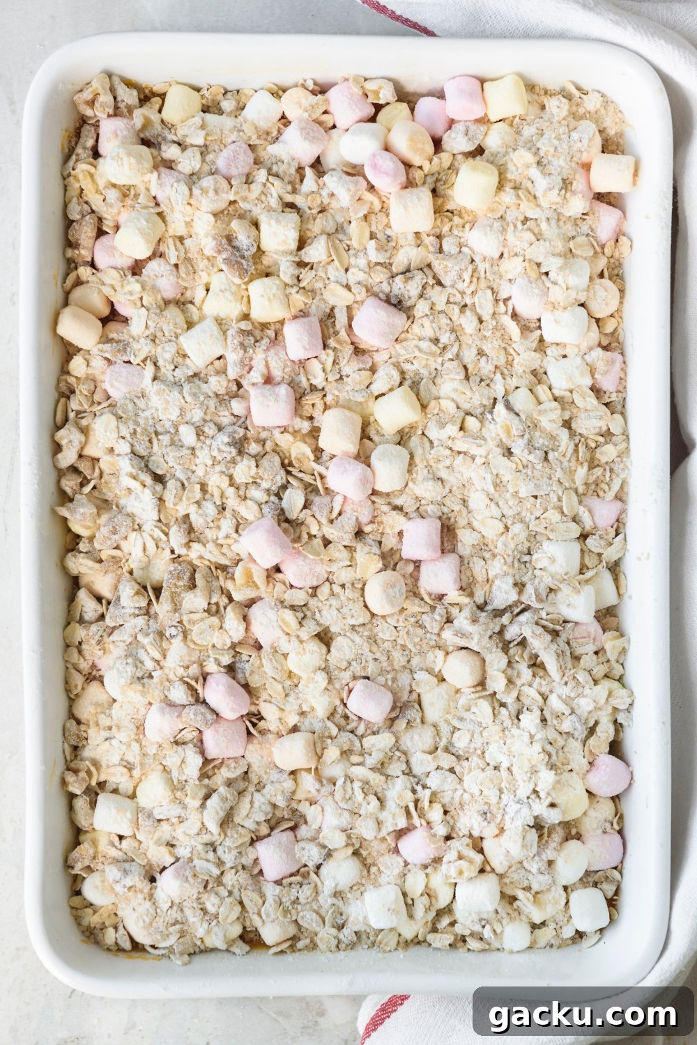 A white casserole dish full of Boston Market Sweet Potato Casserole topped with oat crumble and mini marshmallows.