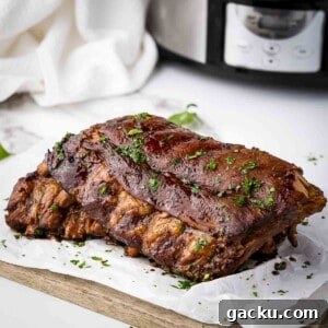 Slow-Cooked Honey Garlic Ribs with Sticky Glaze 9 Side close up shot of multiple ribs garnished with parsely on a piece of butcher paper on a wooden cutting board.