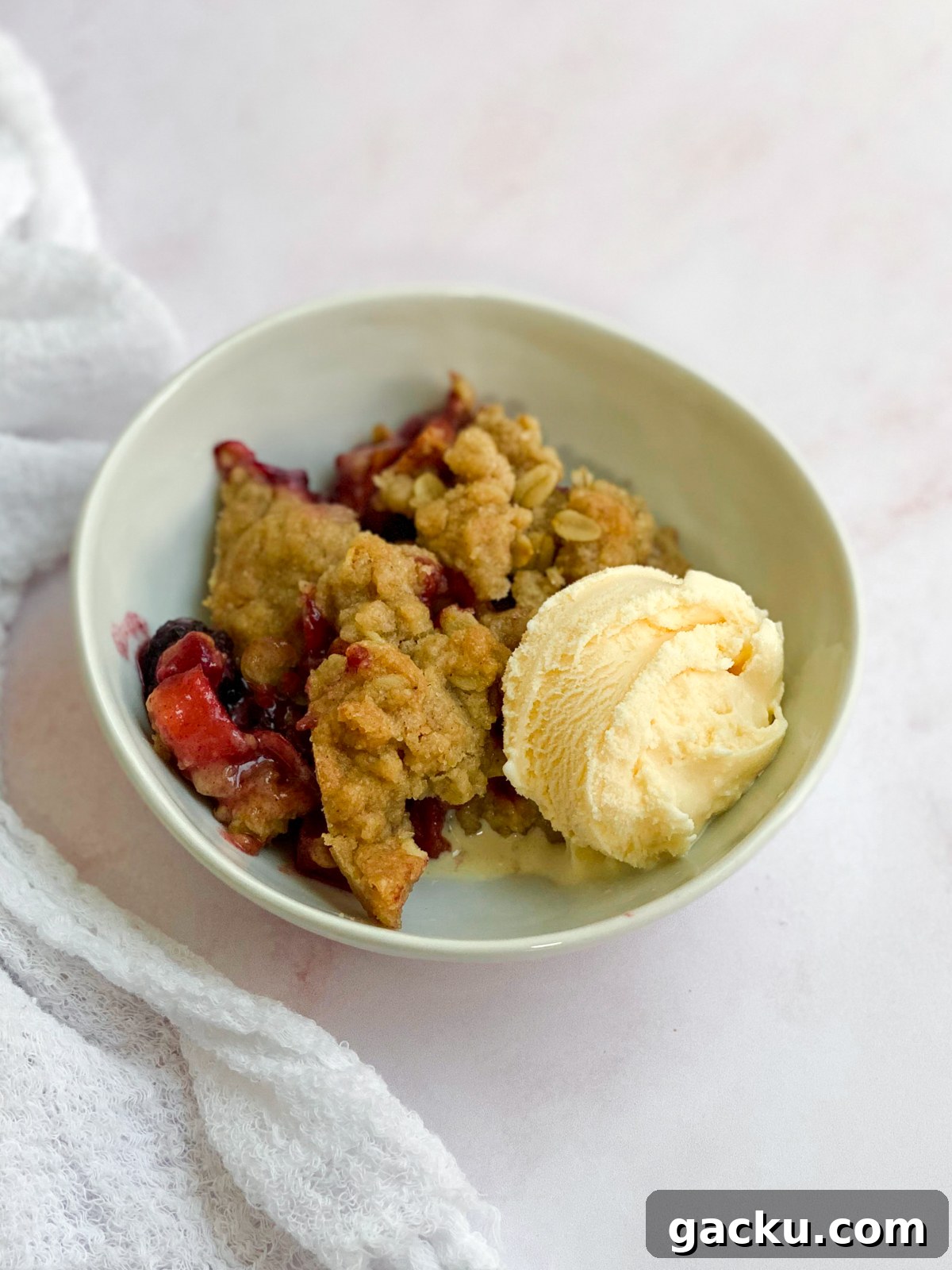 Blackberry Apple Crumble Recipe: Rustic Dessert with Oat Topping 11 a single serving of blackberry and apple crumble in a bowl with some ice cream.