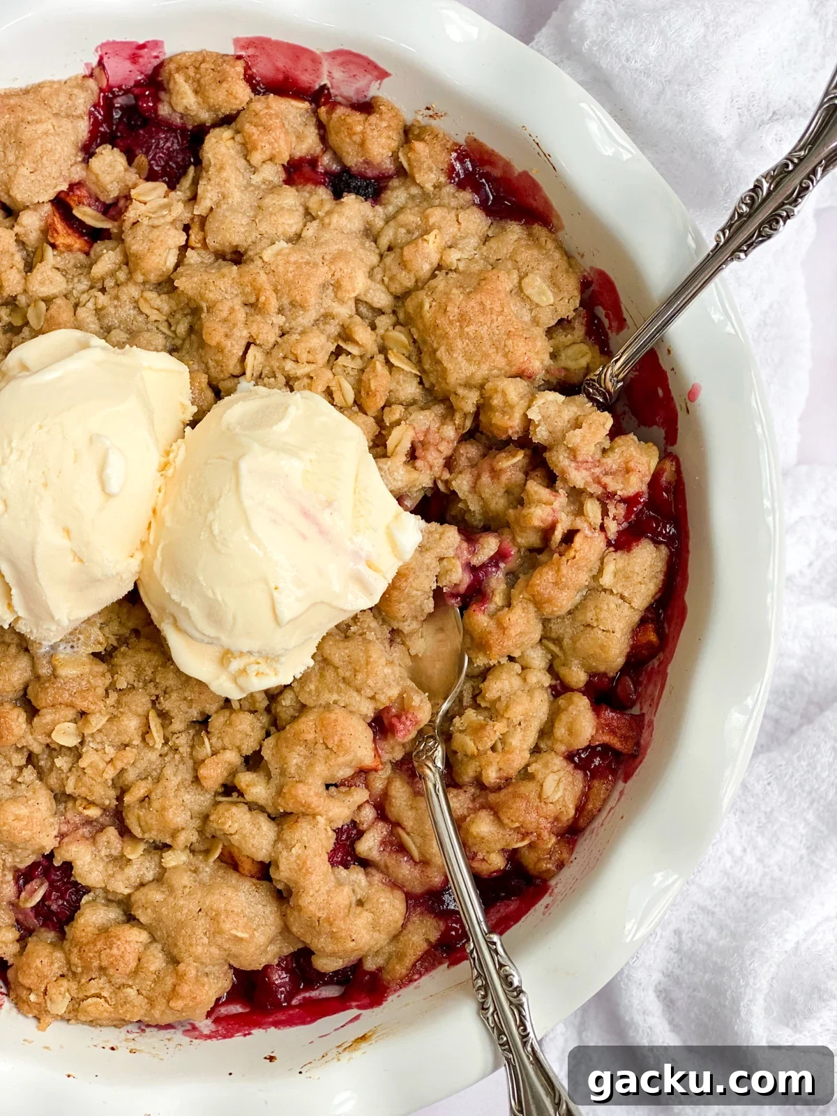 Blackberry Apple Crumble Recipe: Rustic Dessert with Oat Topping 3 close up of the blackberry and apple crumble with 2 scoops of ice cream and 2 spoons in.