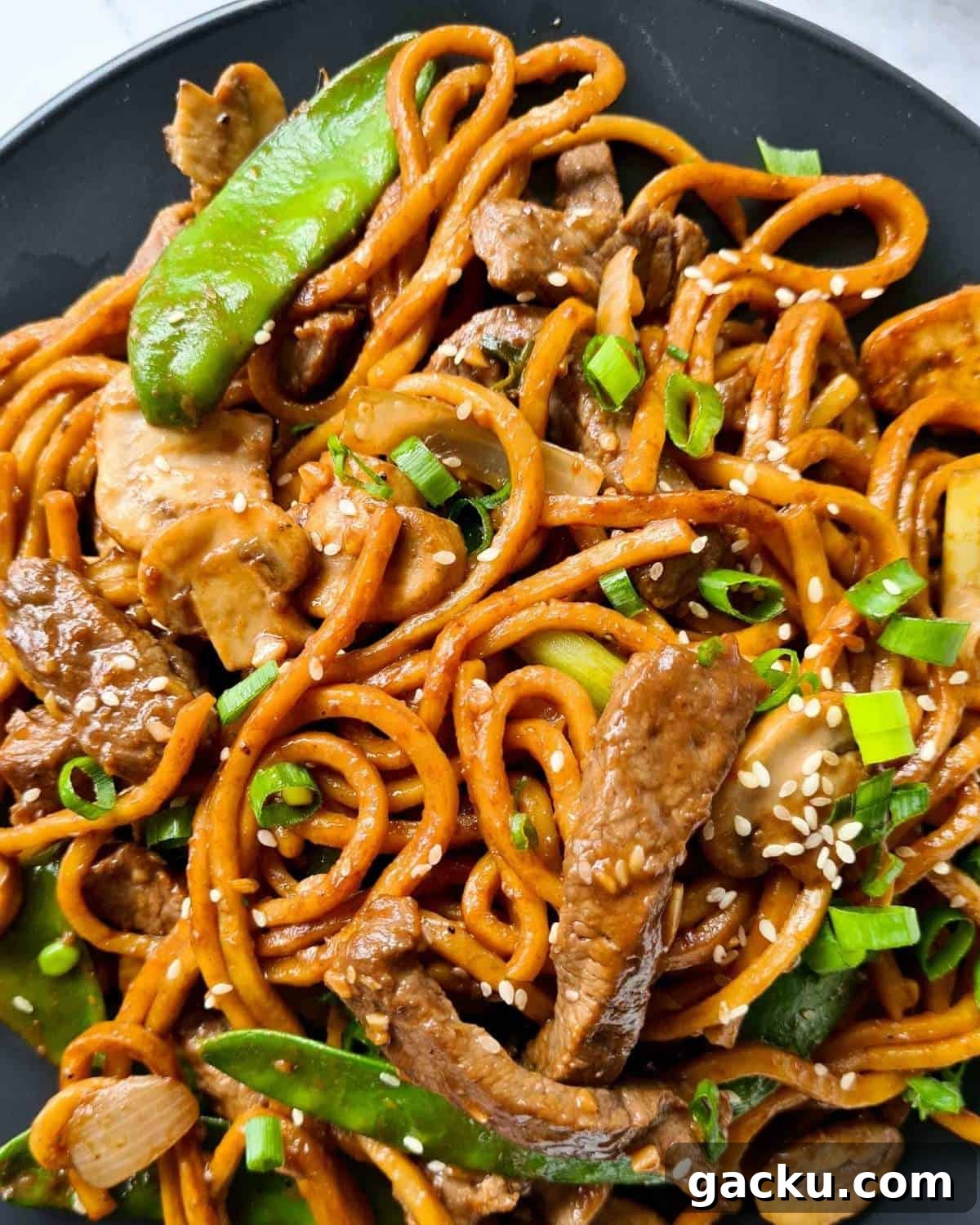 Szechuan Beef Stir-Fry with Noodles: Quick Weeknight Recipe 3 Close up of beef noodles sprinkled with finely sliced spring onions and sesame seeds