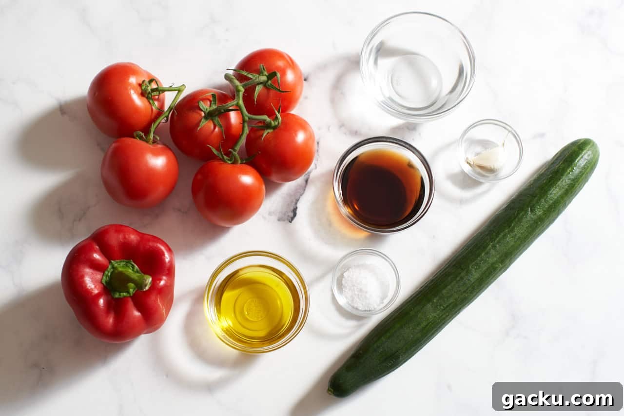Tomatoes, a bell pepper, an English cucumber, and small glass bowls of olive oil, sherry vinegar, salt, garlic and water.