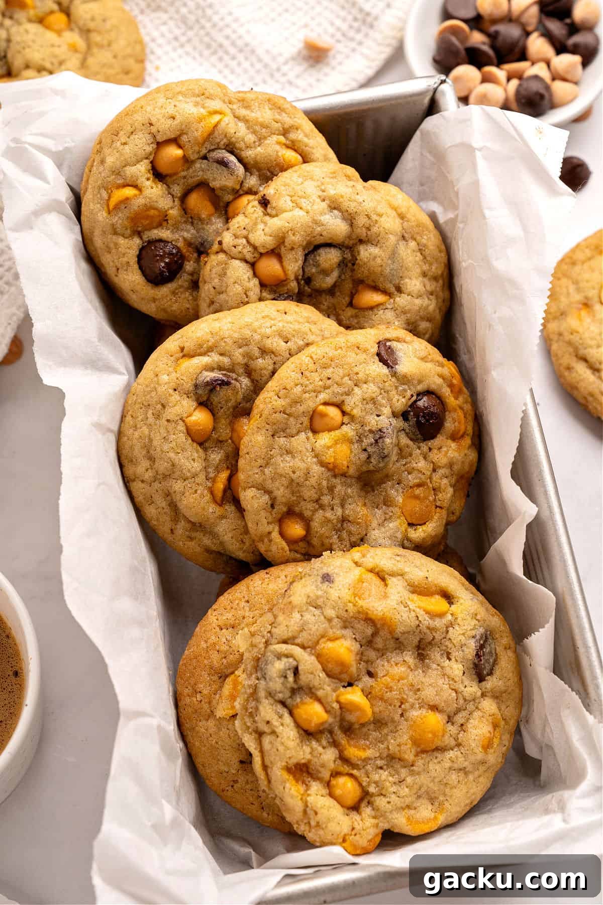 Chewy Butterscotch Chocolate Chip Cookies — No-Chill Dough Recipe 2 Several chocolate butterscotch chip cookies on white paper in a metal loaf pan.