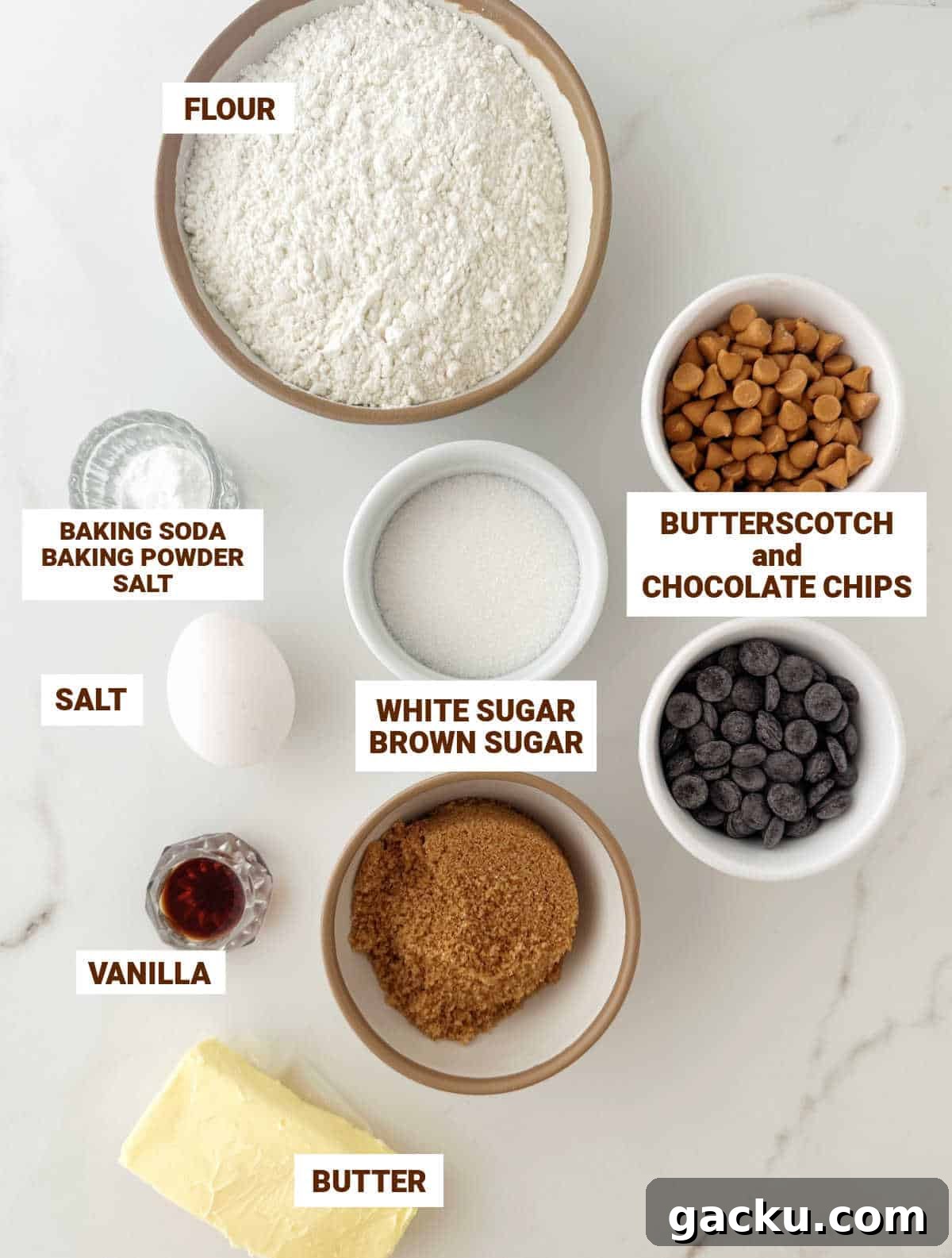 Chewy Butterscotch Chocolate Chip Cookies — No-Chill Dough Recipe 4 White marble surface with bowls containing ingredients for butterscotch chocolate chip cookies including vanilla, butter, egg, flour.