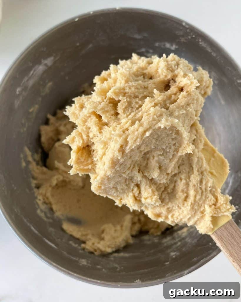 Chewy Butterscotch Chocolate Chip Cookies — No-Chill Dough Recipe 5 Cookie dough on a wooden spoon above the metal bowl with rest of batter.