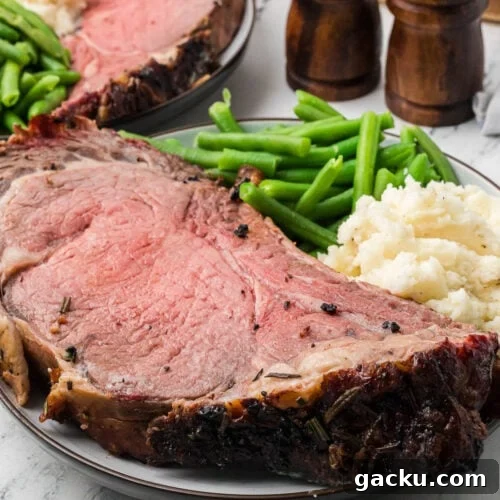 Juicy prime rib roast with green beans and mashed potatoes on a serving plate.