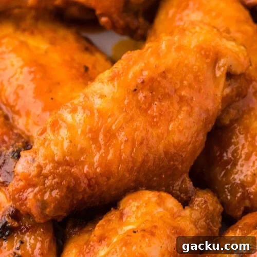 Crispy buffalo chicken wings with spicy orange sauce on a plate.