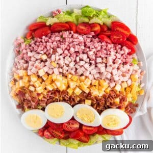 A bowl of Chef salad on the table with all the ingredients laid out in rows.