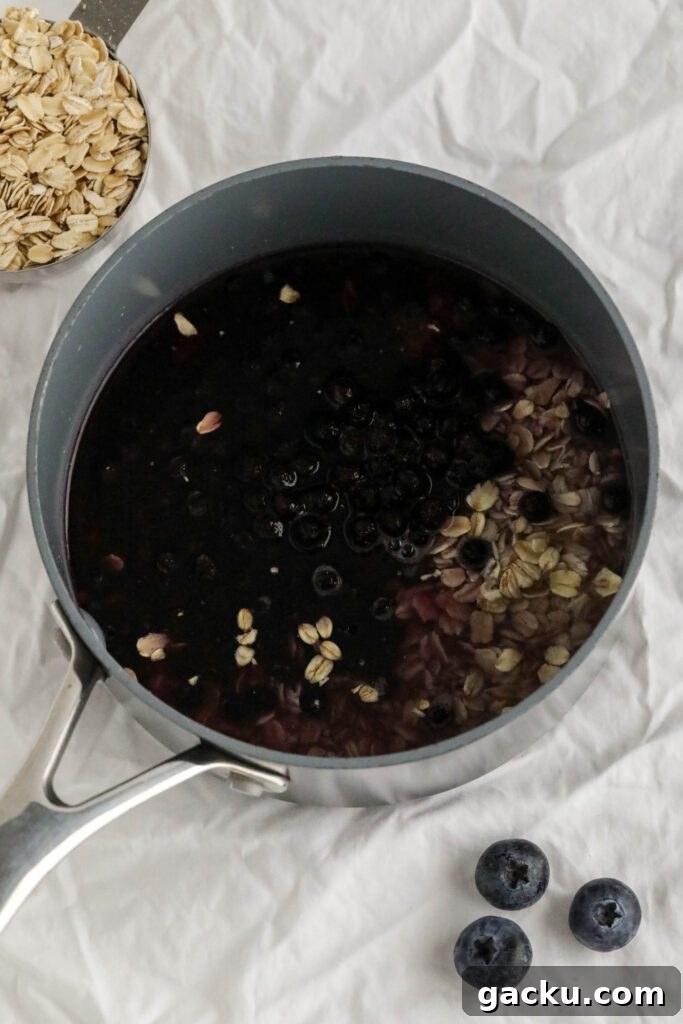 Creamy Blueberry Oatmeal Made on the Stovetop 4 ingredients for blueberry stovetop oatmeal in pot on white towel