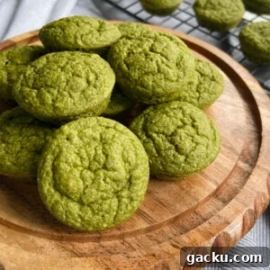 Kid-Friendly Halloween Snack Ideas Kids Will Love 5 Spinach banana muffins served on a wooden plate. Some muffins cooling on a wire rack in the background.