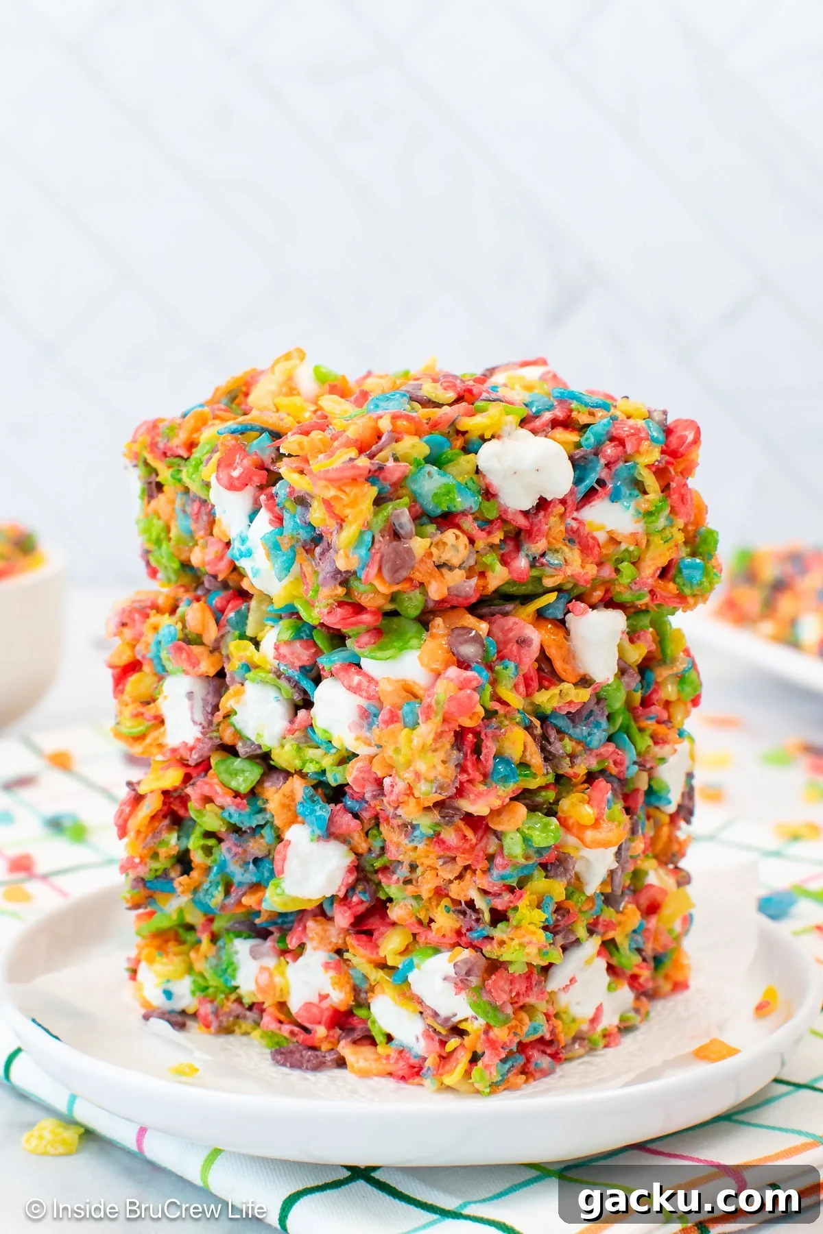 Fruity Pebbles Rice Krispie Treats Recipe 2 A stack of fruity pebbles crispy treats on a white plate.