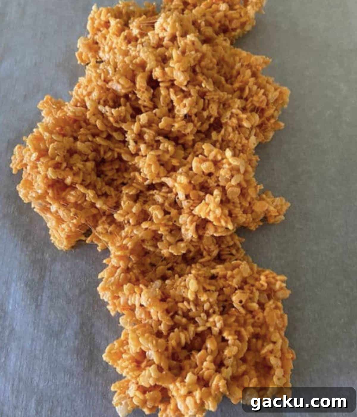 Pumpkin Rice Krispie Treats Recipe for Fall Desserts 6 Rice krispie treats spread on parchment paper.