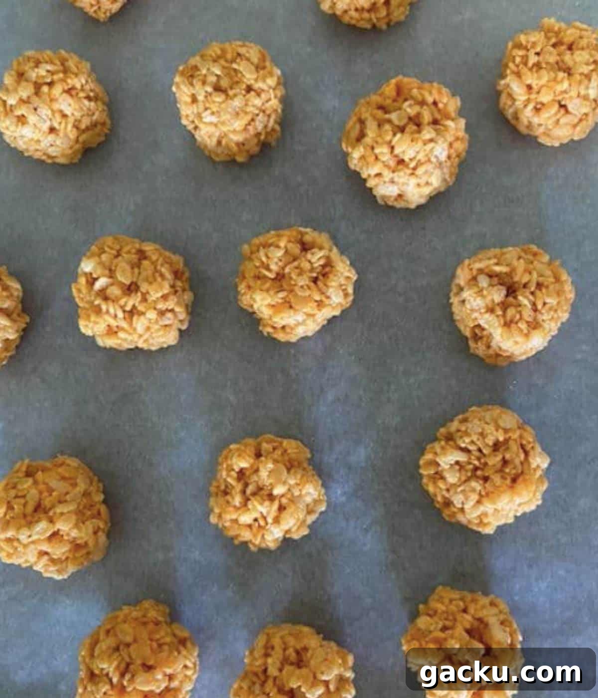 Pumpkin Rice Krispie Treats Recipe for Fall Desserts 8 Rolled rice krispie treats in balls on parchment paper.