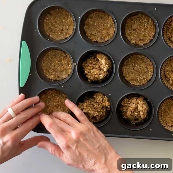 Pressing the crust down into the muffin cups by hand.