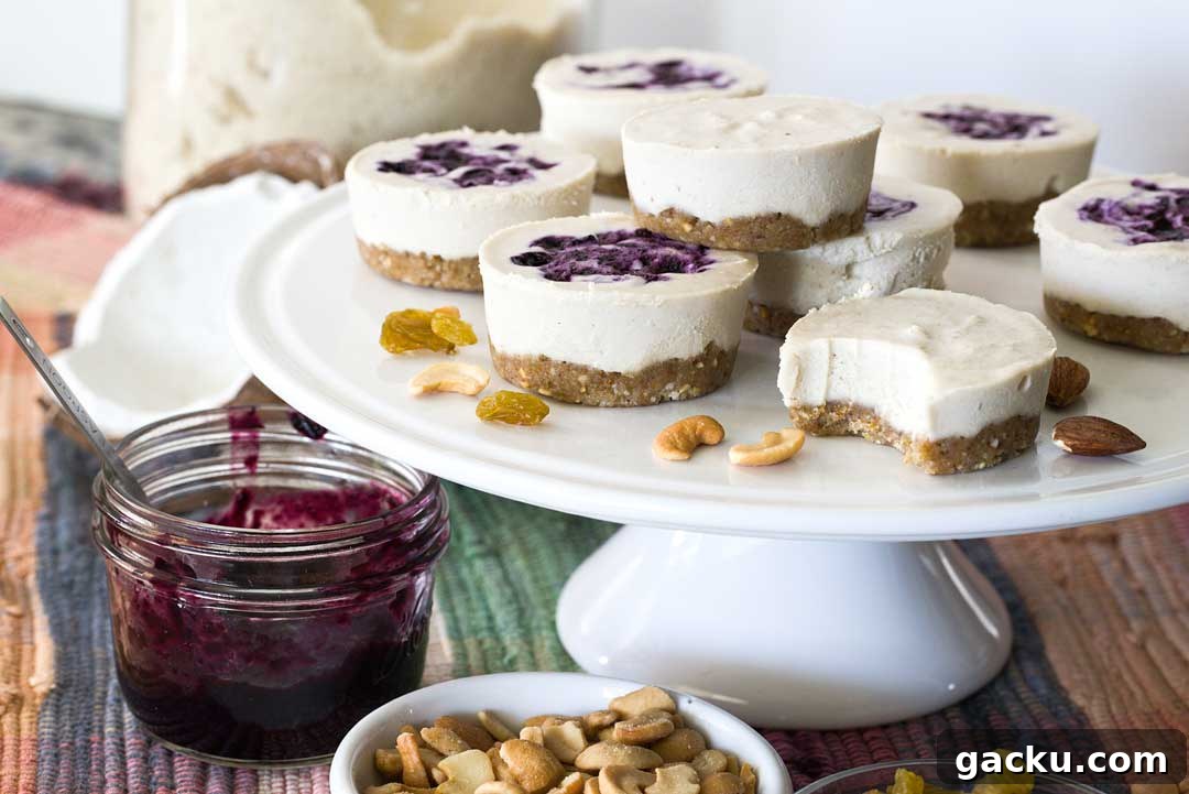 A stack of no bake vegan cheesecakes with blueberry sauce on a cake plate.