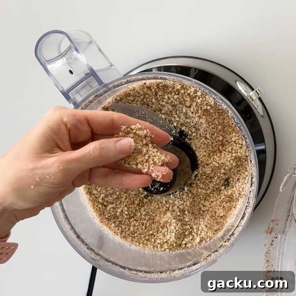 Chopped almonds in the food processor and being held in a hand.